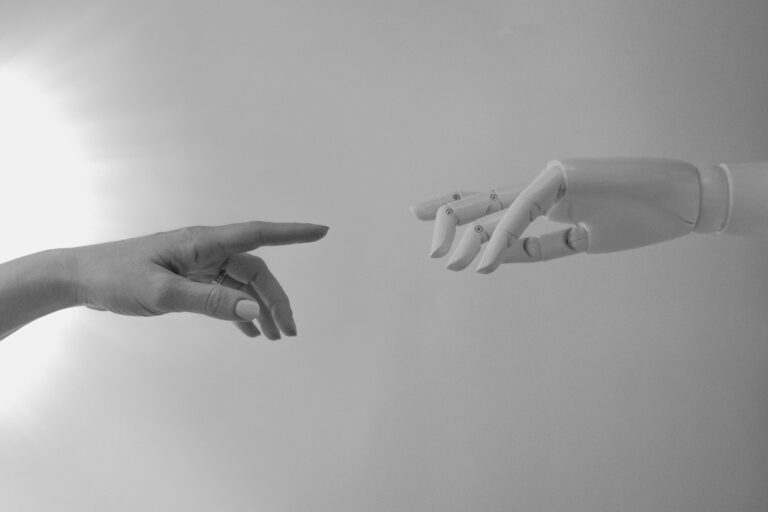 image of a robot and a human hand pointing at each other