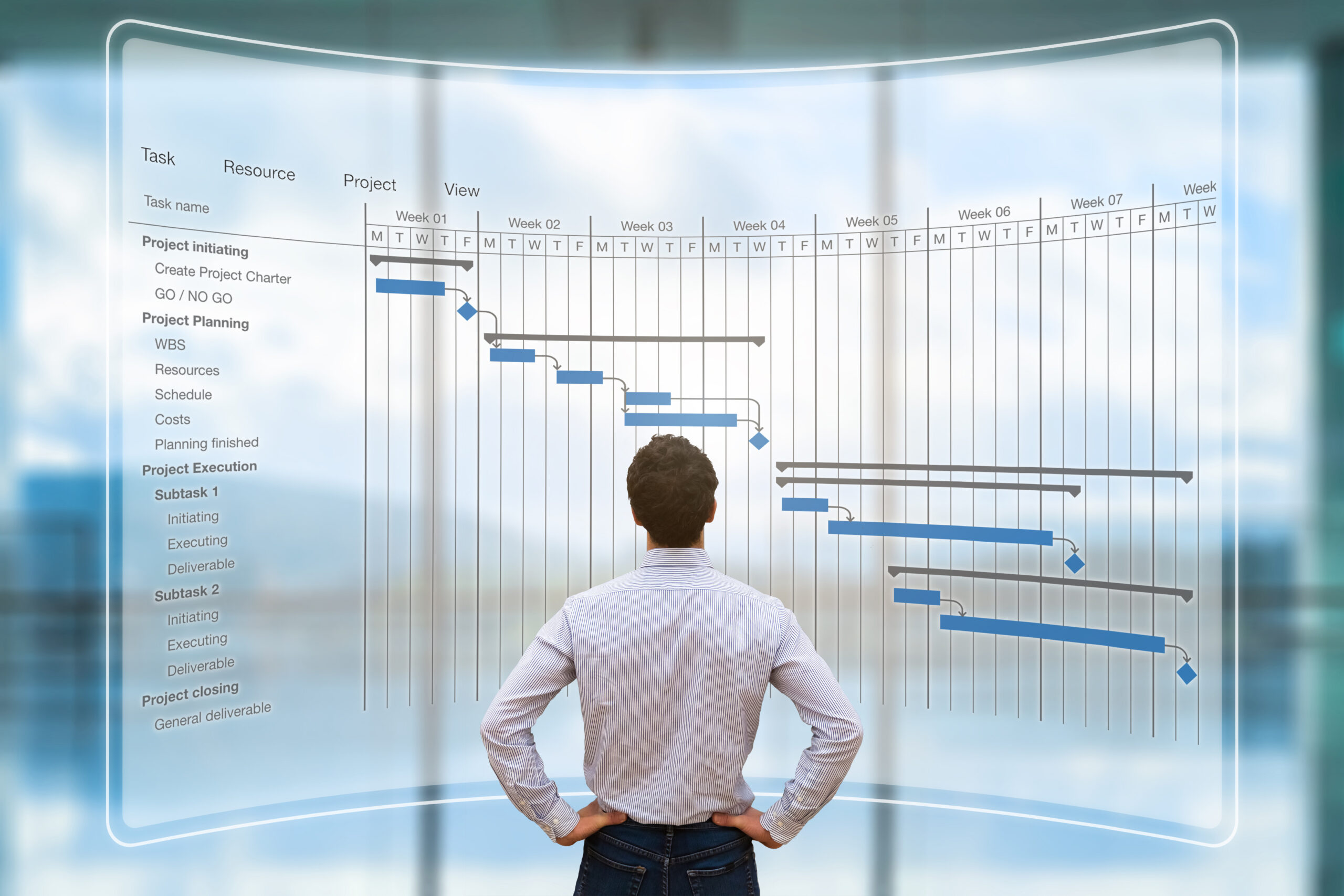 Project manager dresseed in white shirts and brown pants with his back turned to the camera looking at AR screen with Gantt chart
